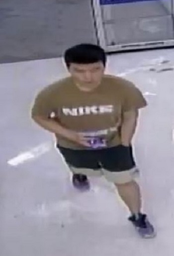 Man wearing a tan/brown shirt with NIKE in white writing, dark shorts with tan trim along the bottom and sneakers.