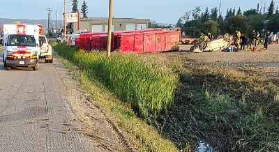 Photo of collision scene with ambulance on the left and white upside down car on the right