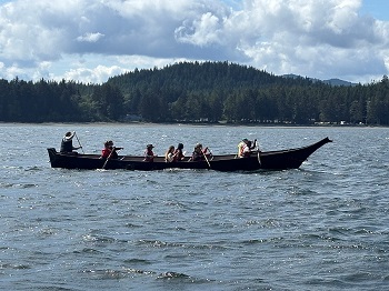 Photo of Indigenous youth paddling with elders in the canoe journey.