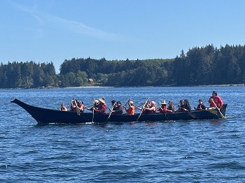 Photo of elders and indigenous community members paddling in the canoe journey.