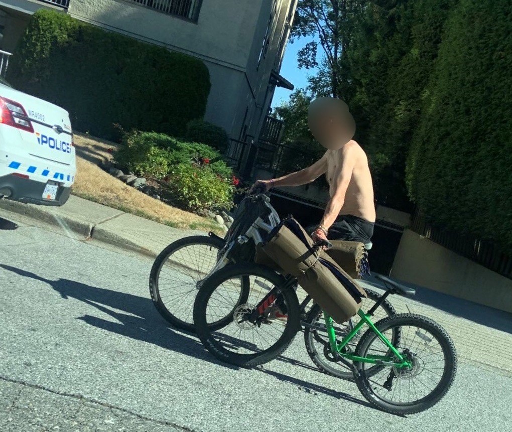 Male riding a bicycle dragging another bicycle by hand