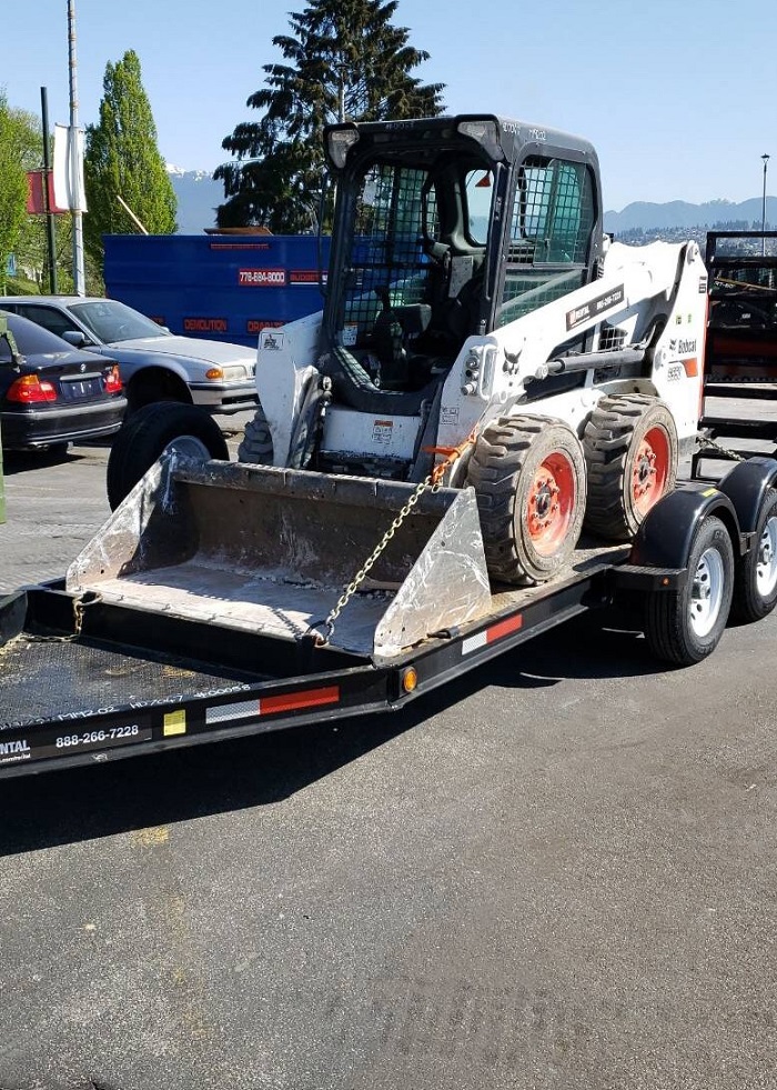 White, black and orange Bobcat bulldozer on trailer