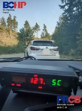 View of police radar through windshield, displaying speed of 127 km/h