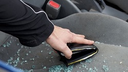 Verre brisé sur le siège de la voiture, bras tendu pour attraper un portefeuille