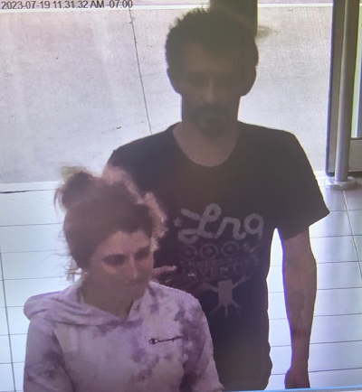 male suspect with dark hair wearing a dark t-shirt and a female suspect with red hair, in a bun, wearing a pink and white Champion hoodie