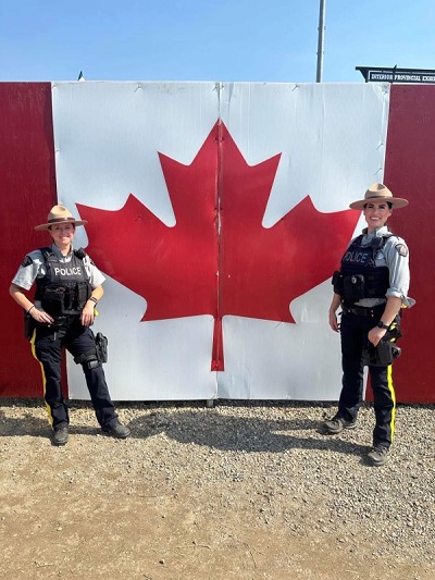 RCMP officers posing in front of Canadian flag at the 2023 IPE.