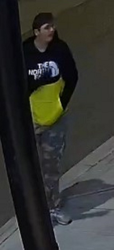 Adolescent qui a de courts cheveux foncés et qui porte des lunettes, un chandail noir et jaune à capuchon de marque The North Face ainsi qu’un pantalon à motif de camouflage.